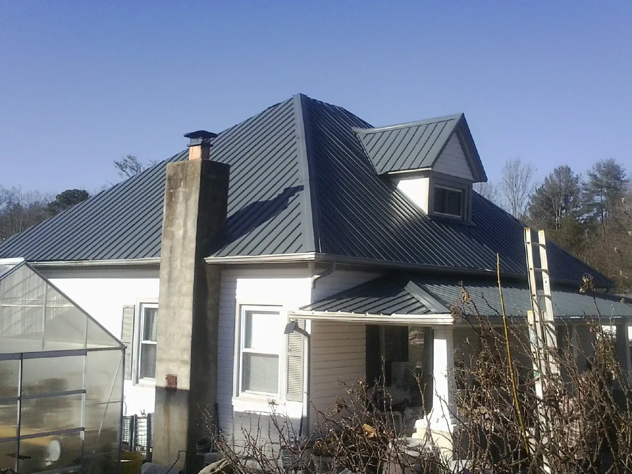 Dark blue standing seam metal roof on a white farmhouse with dormer — Slate & Tile Roof Repair by Roofing Brothers in Deer Grove