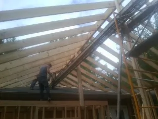 Rafters going up over a new addition with a worker on the wall in Deer Grove