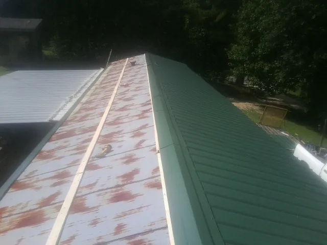 Old rusted panels beside newly installed green metal roofing — Wind Damage Roof Repair by Roofing Brothers in Deer Grove