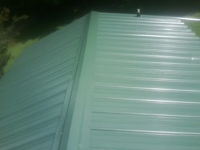 New green metal panels meeting at the ridge of a roof — Flat Roof Repair work by our crew in Deer Grove
