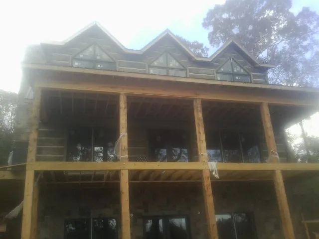 Dormers and porch framing on a large log home under construction — Roof Coating work by our crew in Deer Grove
