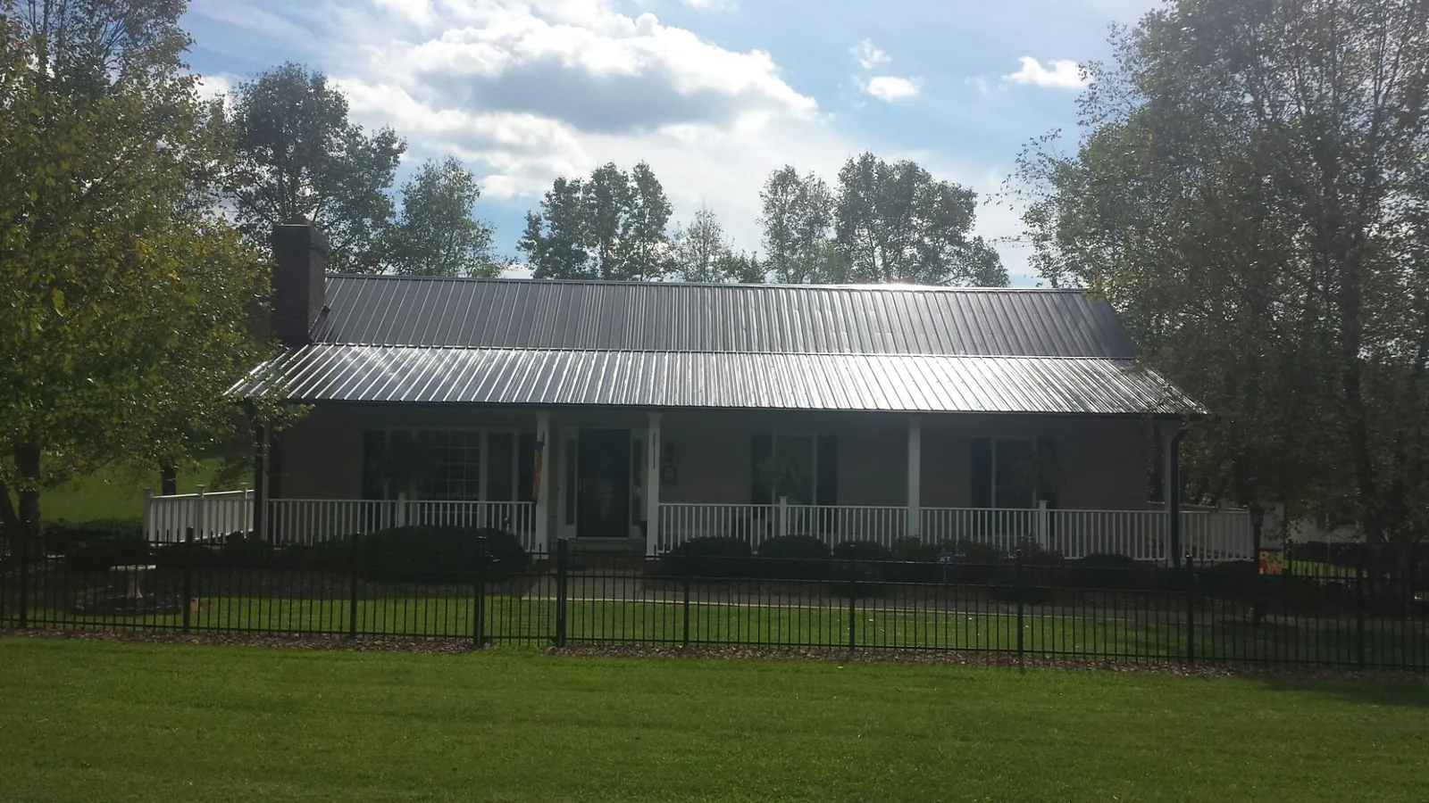Gray metal roof on a brick ranch with a full width front porch — Gutter Guard Installation work by our crew in Deer Grove