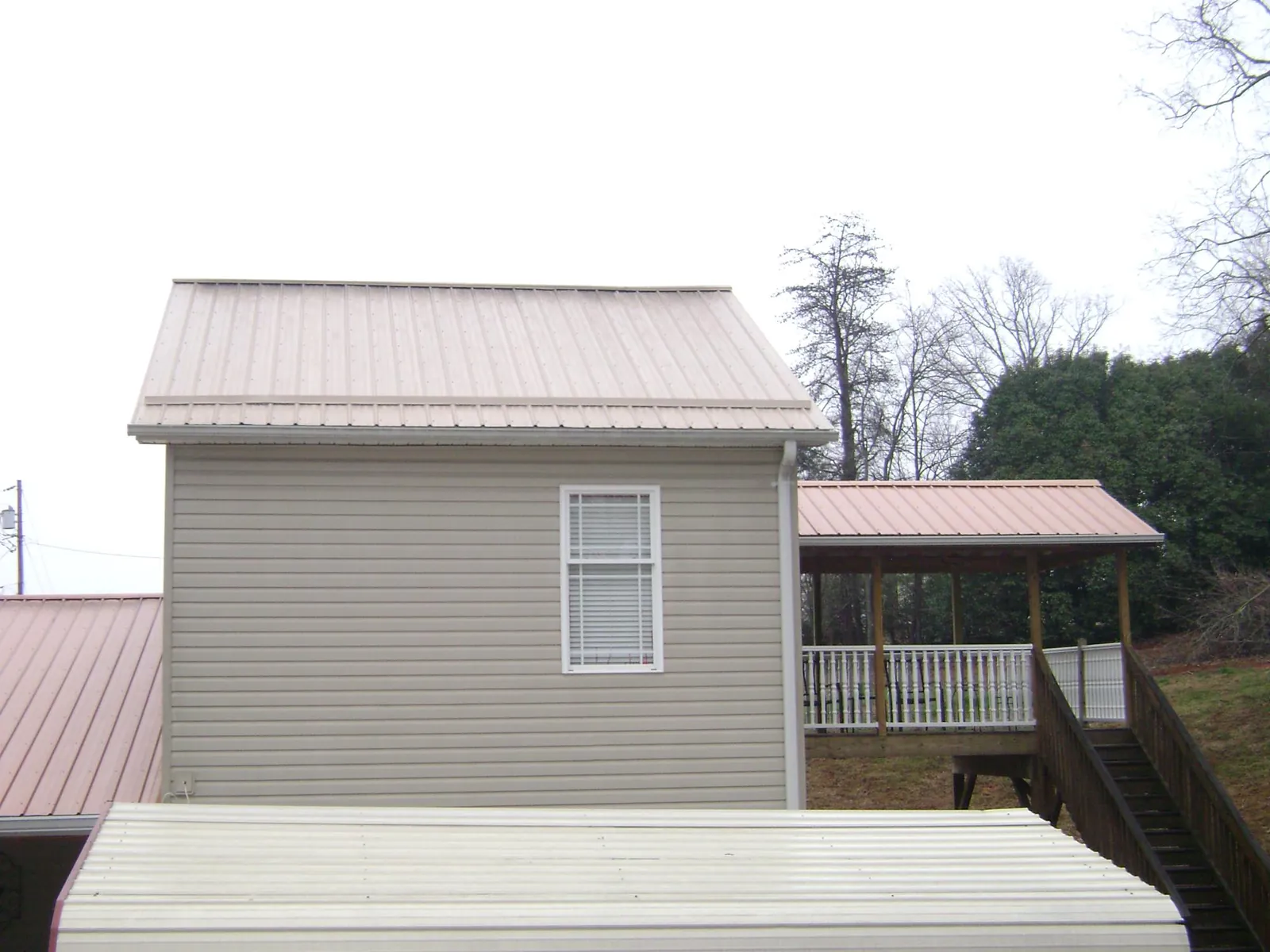 Tan metal roofs on a two story addition and attached porch, from a Roof Replacement job in Deer Grove