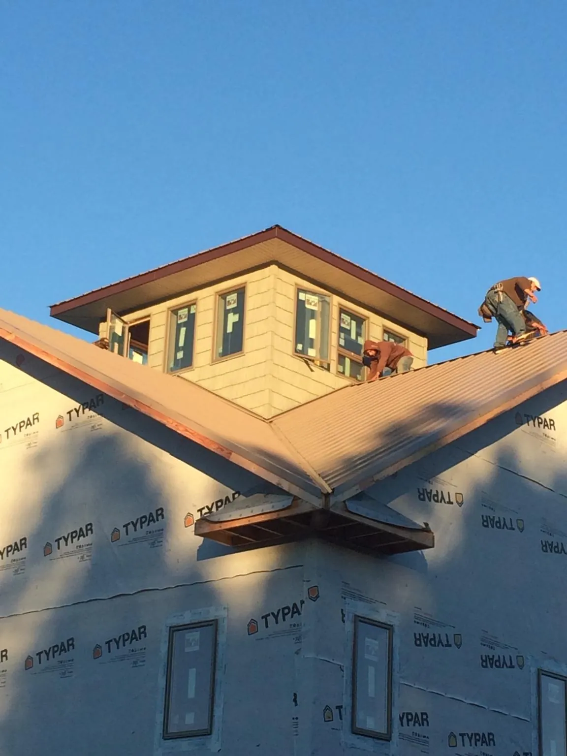 Roofers working around a rooftop cupola on a new metal roof at sunset — Roof Waterproofing in Deer Grove by Roofing Brothers